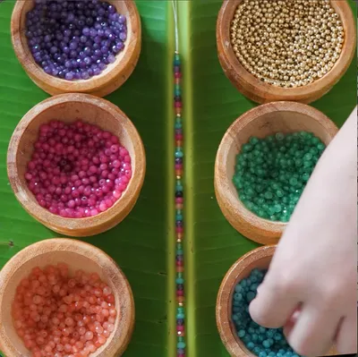 Timelapse of Lucky Charm beads being sorted and strung from wooden bowls